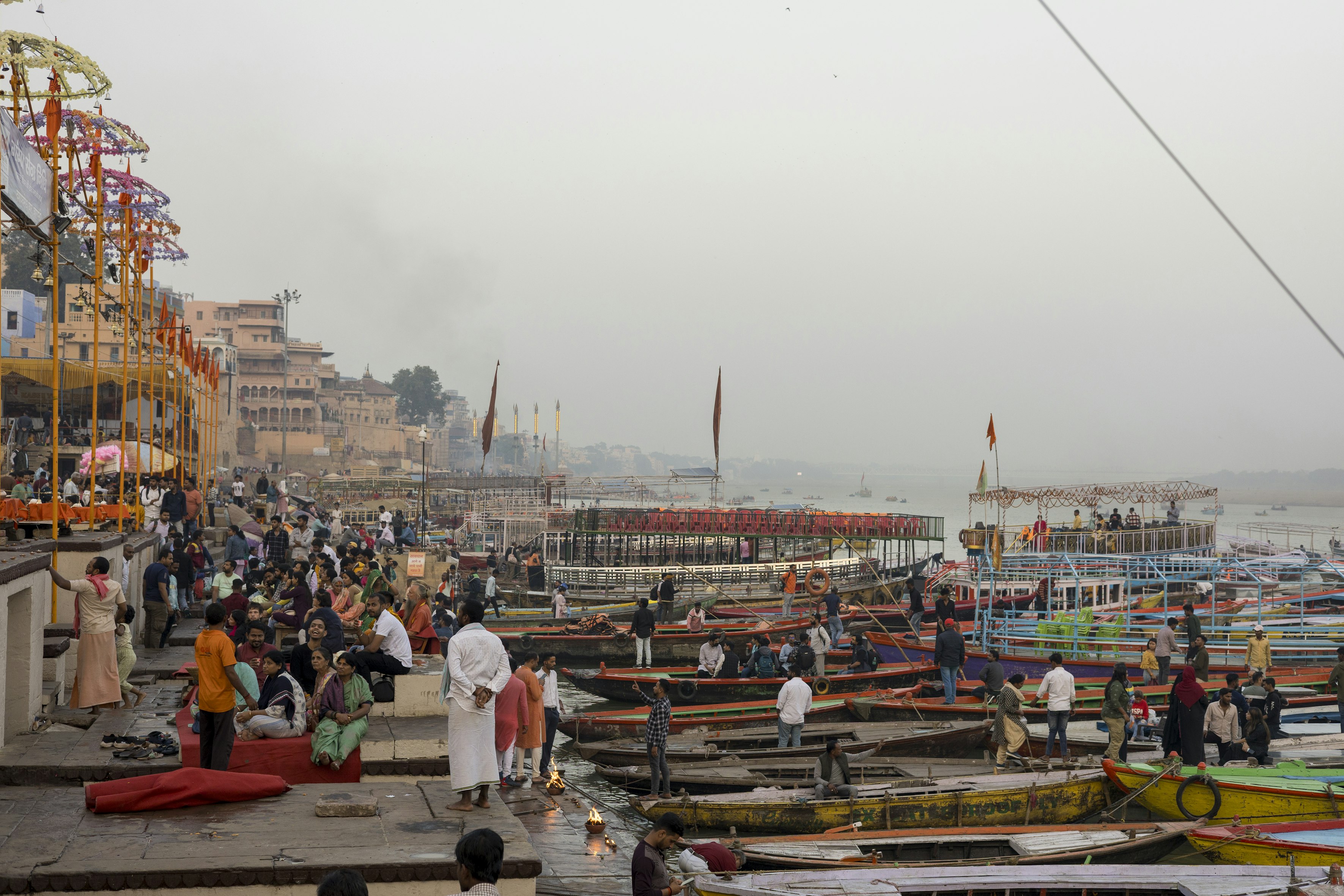 A rainy Ganga ghat shot with diyas and boats