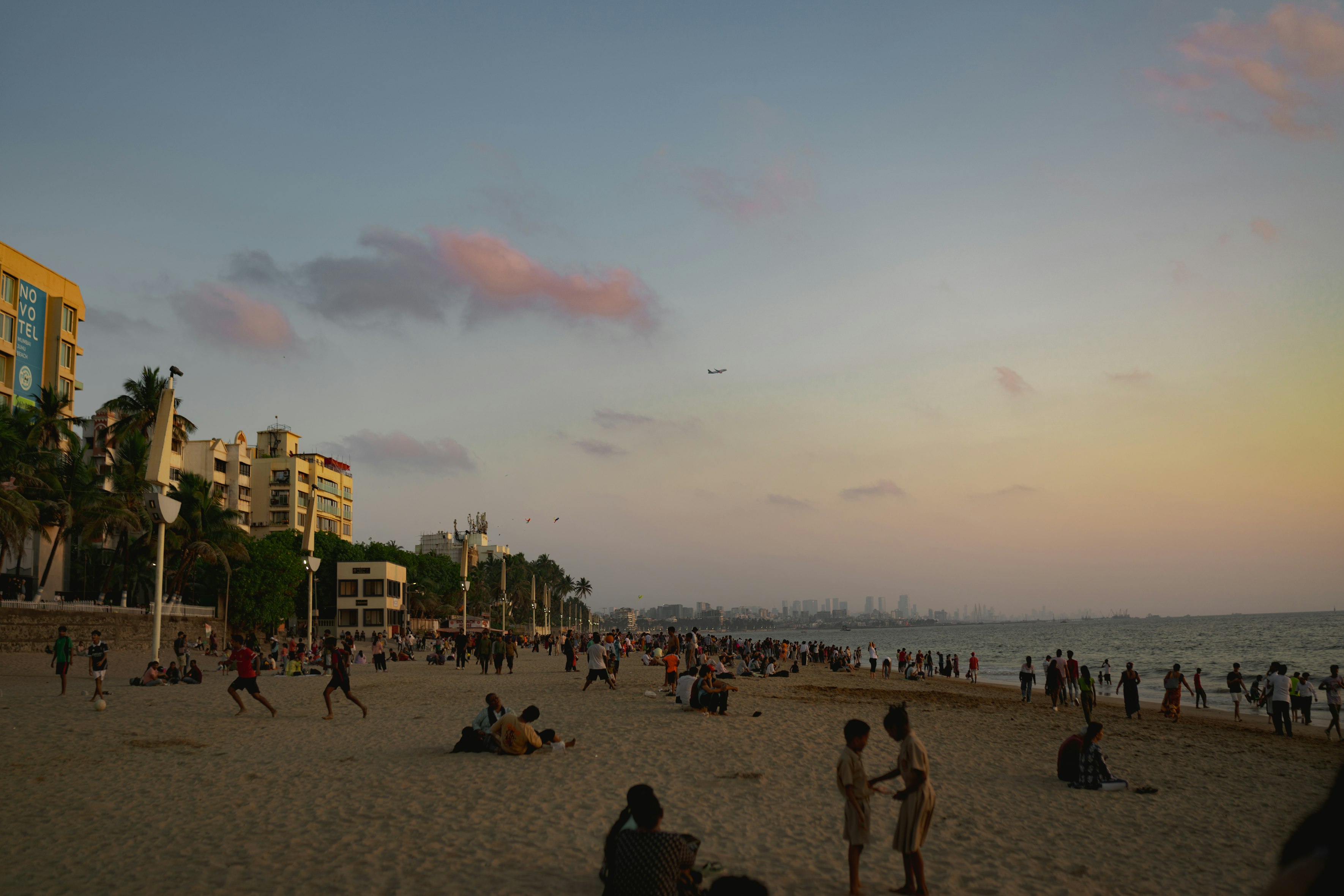 Beachside club with string lights, ocean view, and people enjoying drinks at sunset